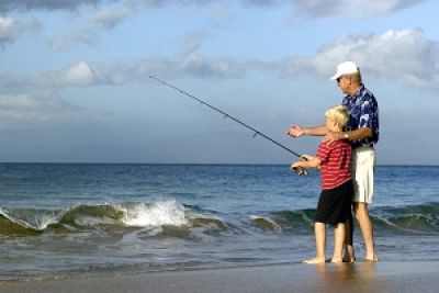 Grandfather and grandson fishing on beach